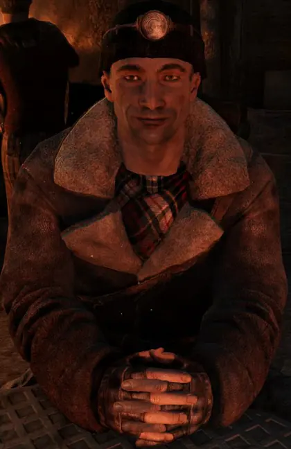 A man smiling warmly in a dimly lit room.